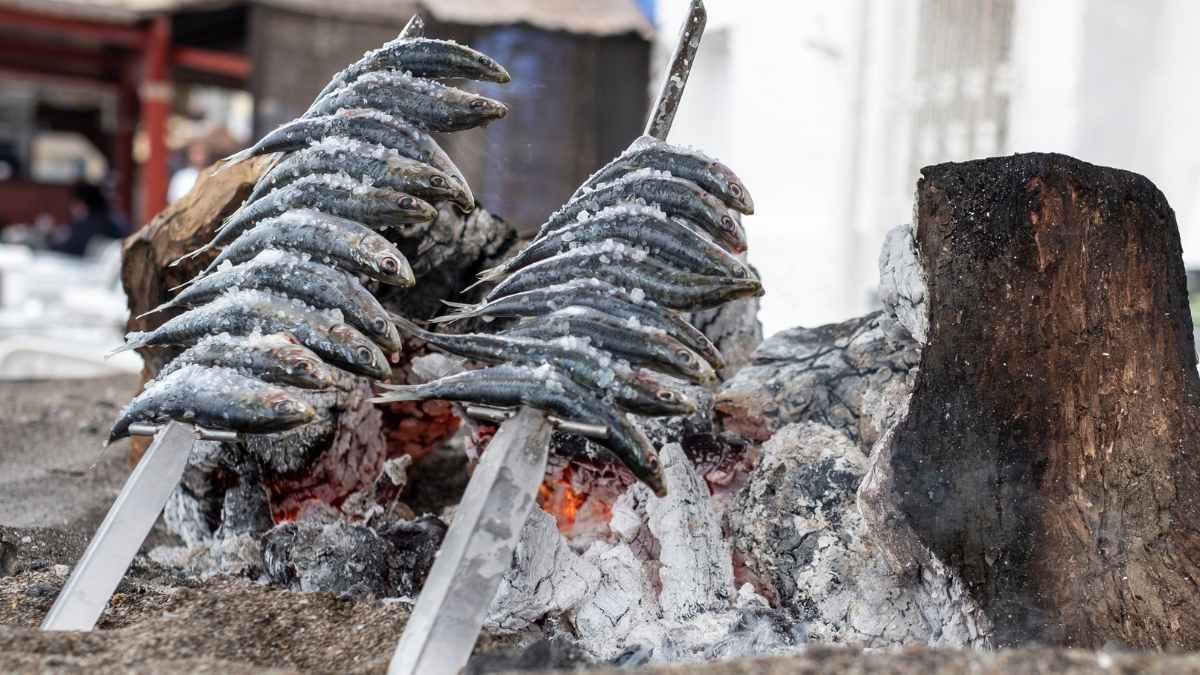 Sardine espetos grilling over embers on a Fuengirola beach